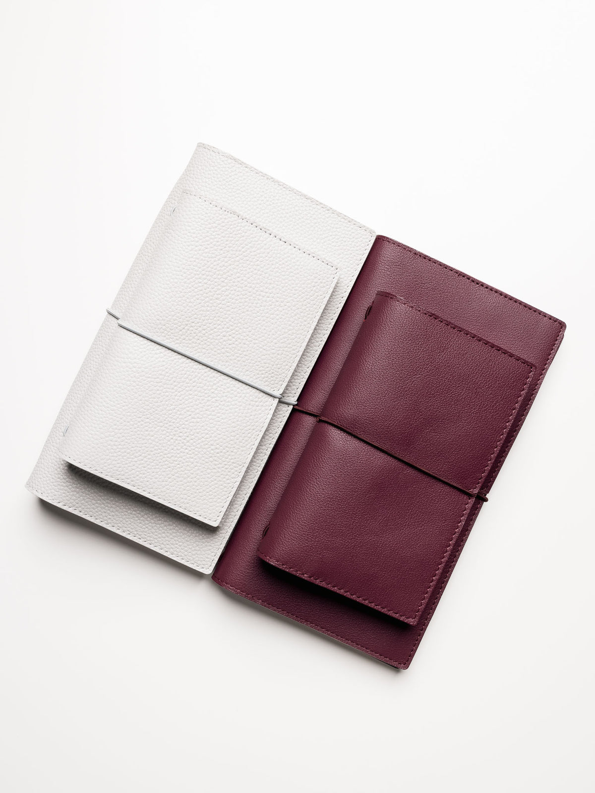 Red and grey genuine leather travel notebook covers shown with Pocket Plus size on top of A5 Slim size.
