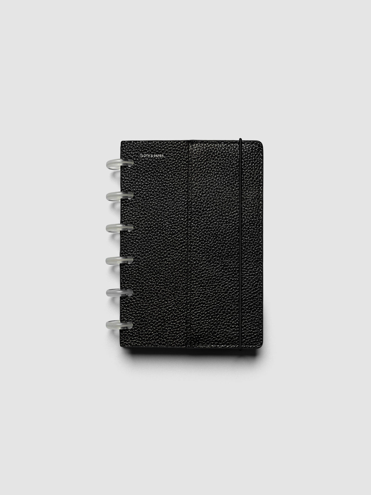 The CP Petite 6-Disc Punch Genuine Leather Planner Cover Set closed on a ring bound planner, showing the silver rings, the silver foiled logo, and the bungee cord holding the stack shut