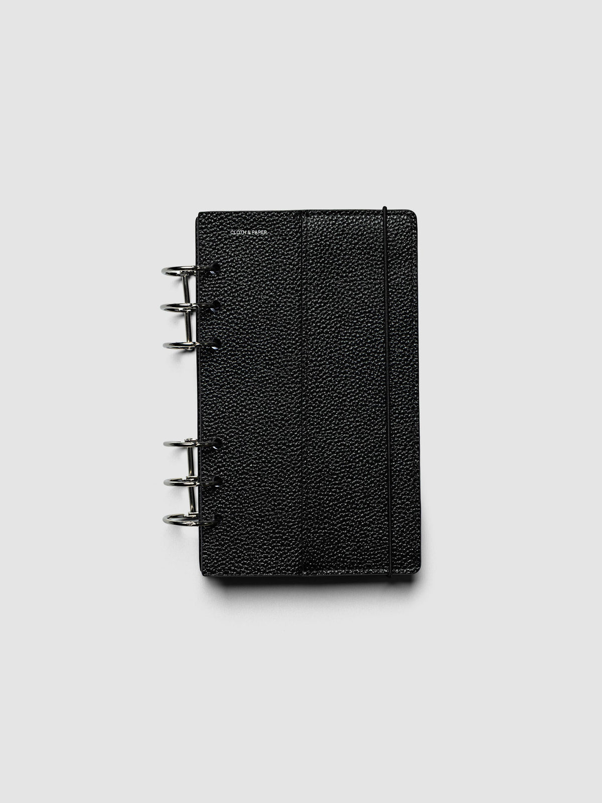 The Personal Genuine Leather Planner Cover Set closed on a ring bound planner, showing the silver rings, the silver foiled logo, and the bungee cord holding the stack shut