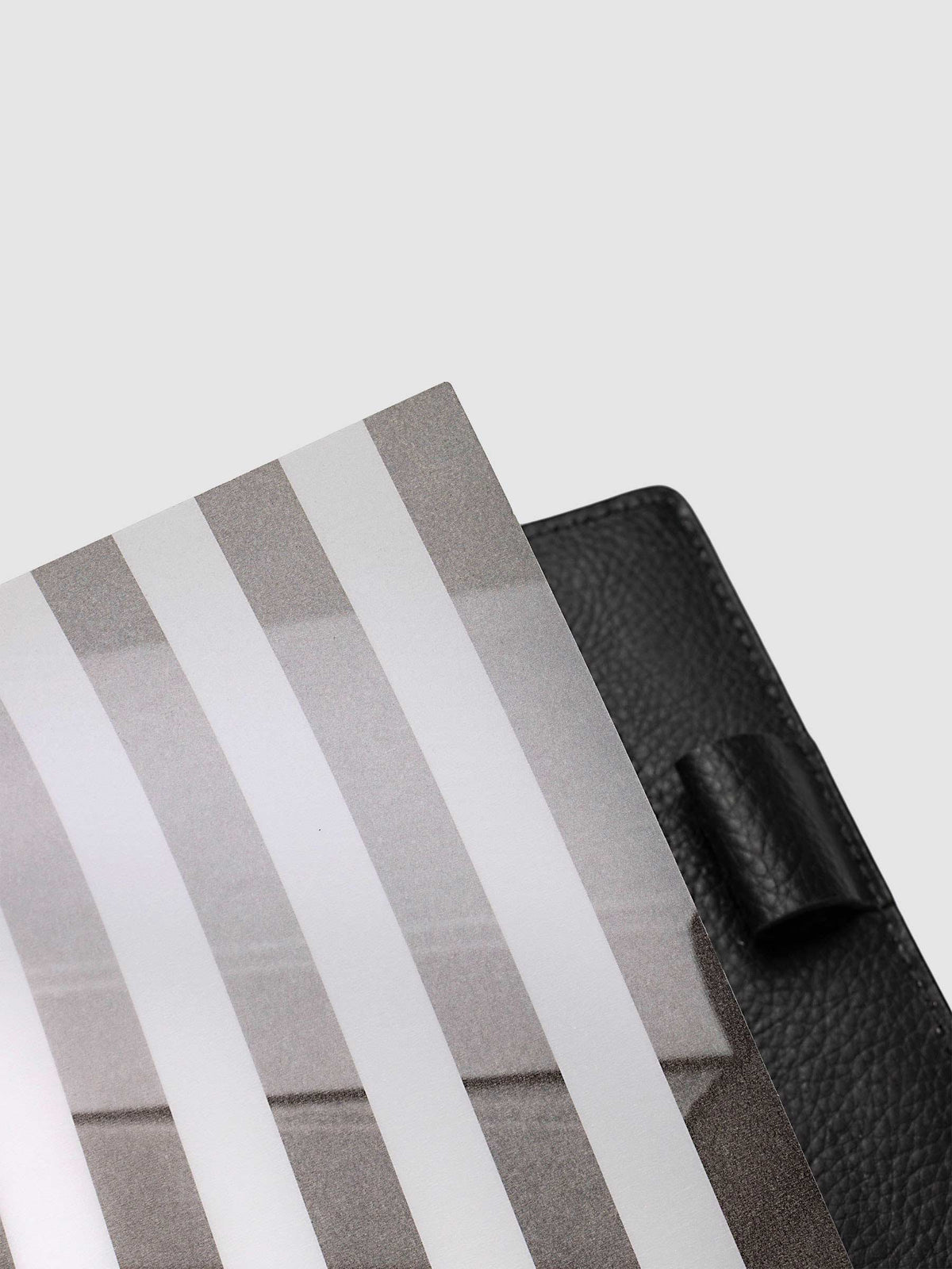 Close-up of the top corner of the vellum base layer of the Half Letter 8-Disc Punch Strips Planner Dashboard Duo, showing the matte printed strips against a black pebbled leather cover
