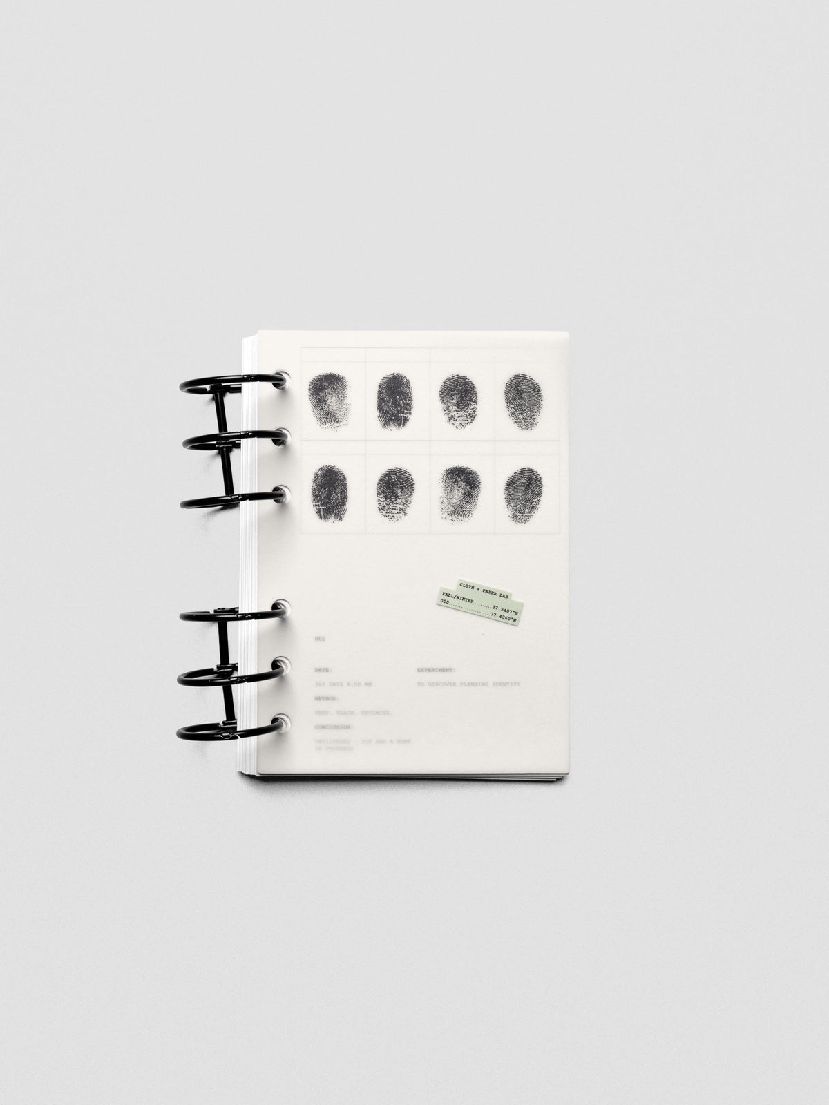 Two layered A6 sized planner dashboards, one semi-transparent, one matte, featuring a fingerprint design shown in a ring bound planner.