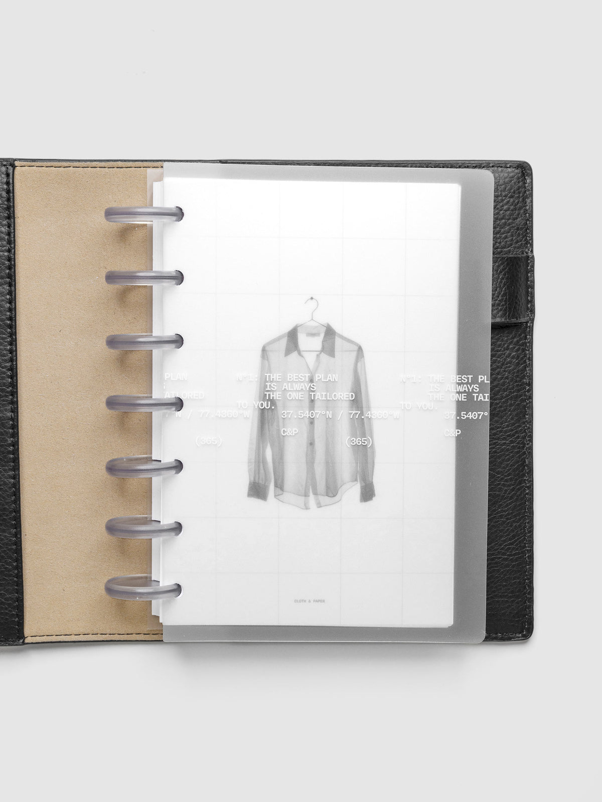 Transparent planner cover set with white printed text design and accompanying black and white dashboard with an image of a tailored shirt on a hanger. Shown discbound in a black leather folio in size HP Mini.