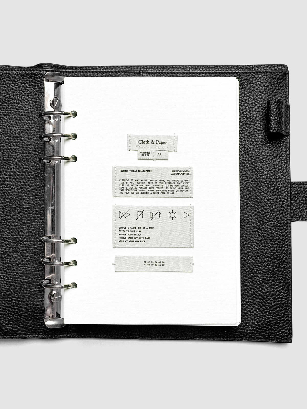 Sewn Tags Planner Dashboard pre-punched for 6-ring planners in size A5 shown in a black leather agenda.