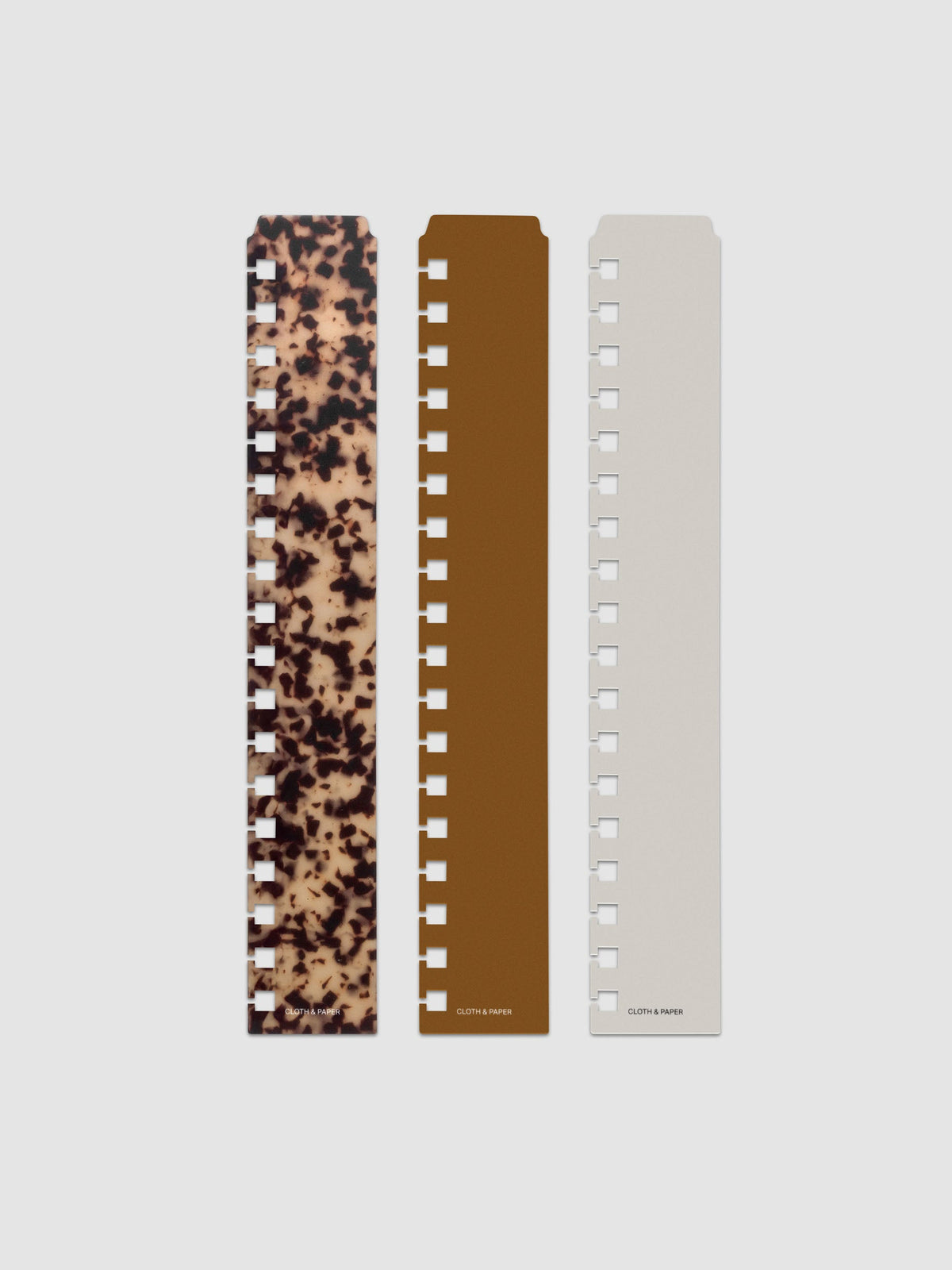 Narrow Page Marker Set Vol. 2, a set of 3 page markers for planners and notebooks shown in size HP Classic Spiral. Includes one tortoiseshell pattern, one solid brown, and one solid grey page marker.