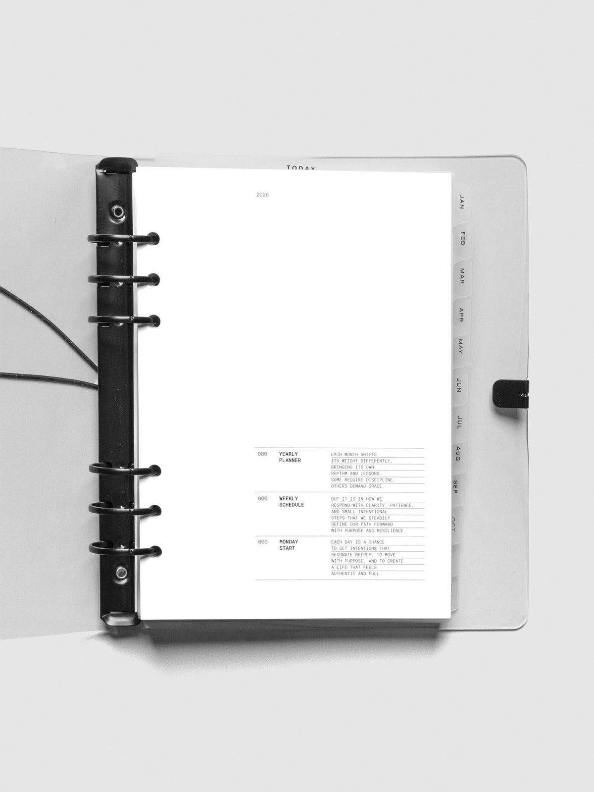 Open view of the A5 6-ring planner with a clear cover, displaying the 2026 title page and first intro page that includes descriptions for yearly planning, weekly scheduling, and Monday start. Tabs for January through May are visible on the right.