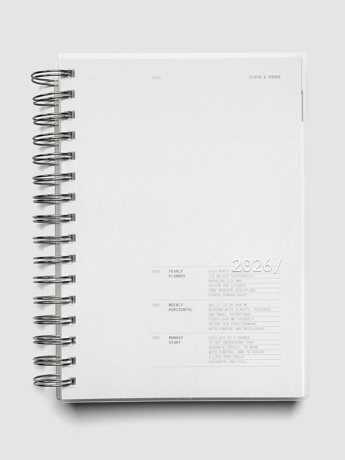 A5 size, silver spiral bound 2026 planner shown closed laying flat on a neutral background.