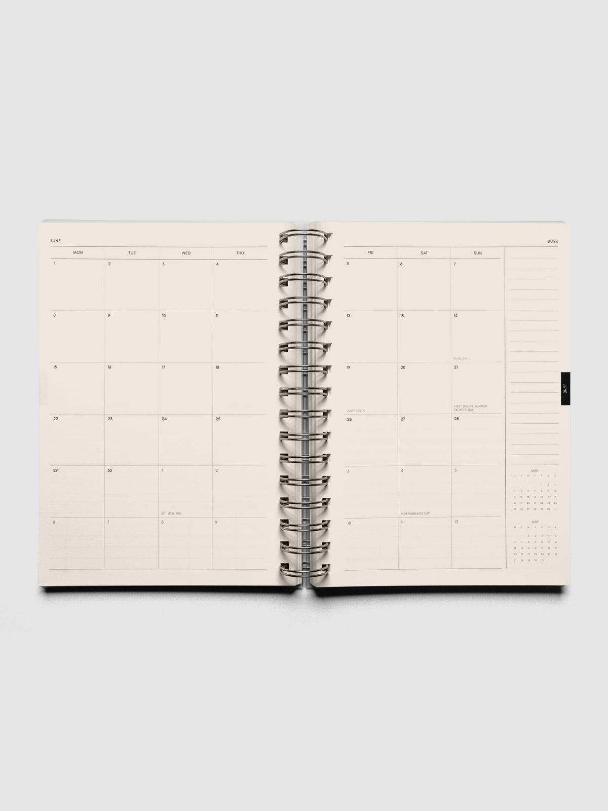 Open spiral notebook showing a monthly calendar layout with a lined notes section on the right hand side above a month-at-a-glance view.