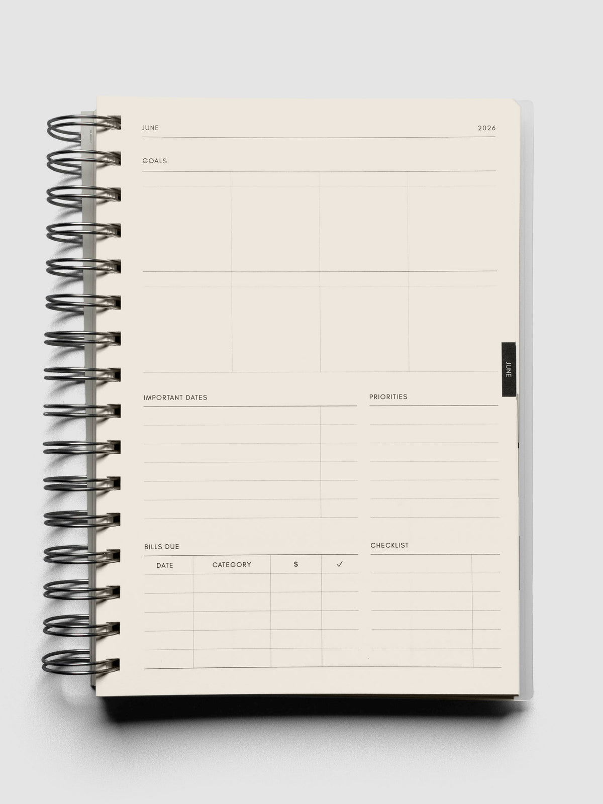 Open spiral notebook showing a monthly page with fields for goals, important dates, priorities, bills due, and checklists.
