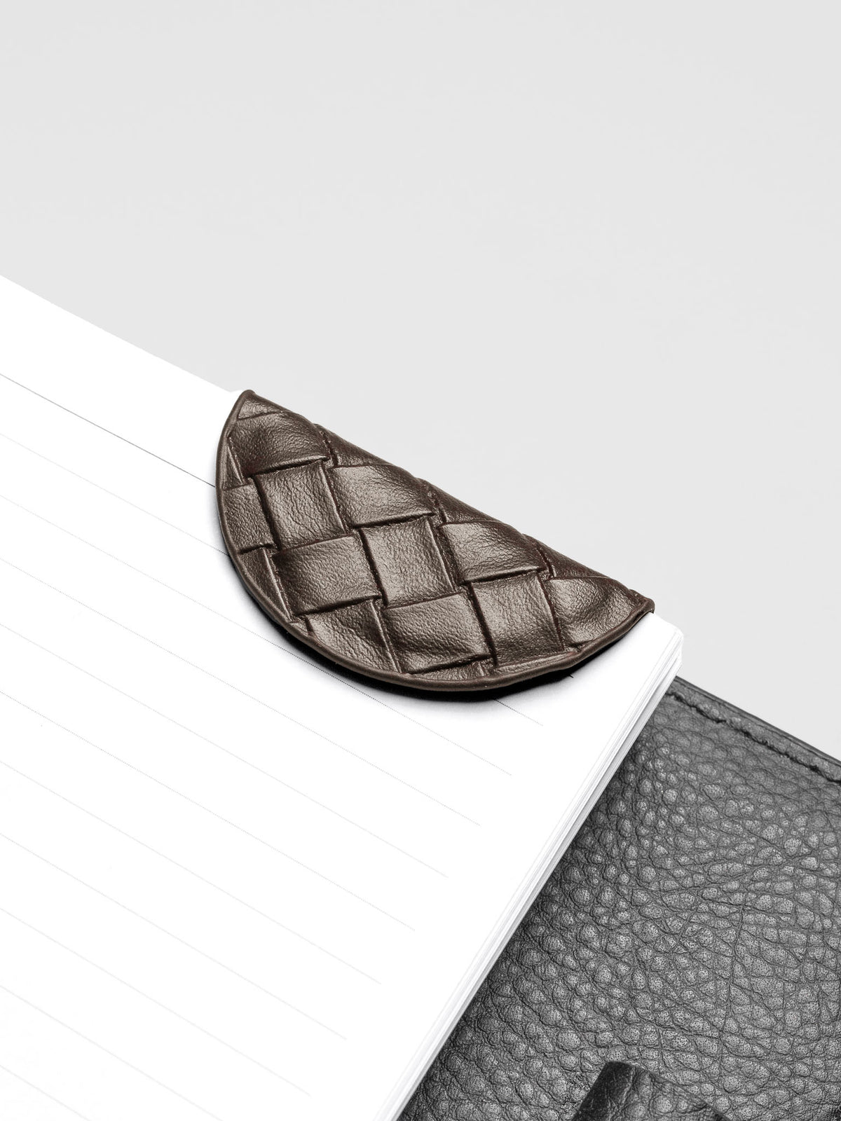 Woven vegan leather magnetic bookmark in the color walnut shown in use with a planner.