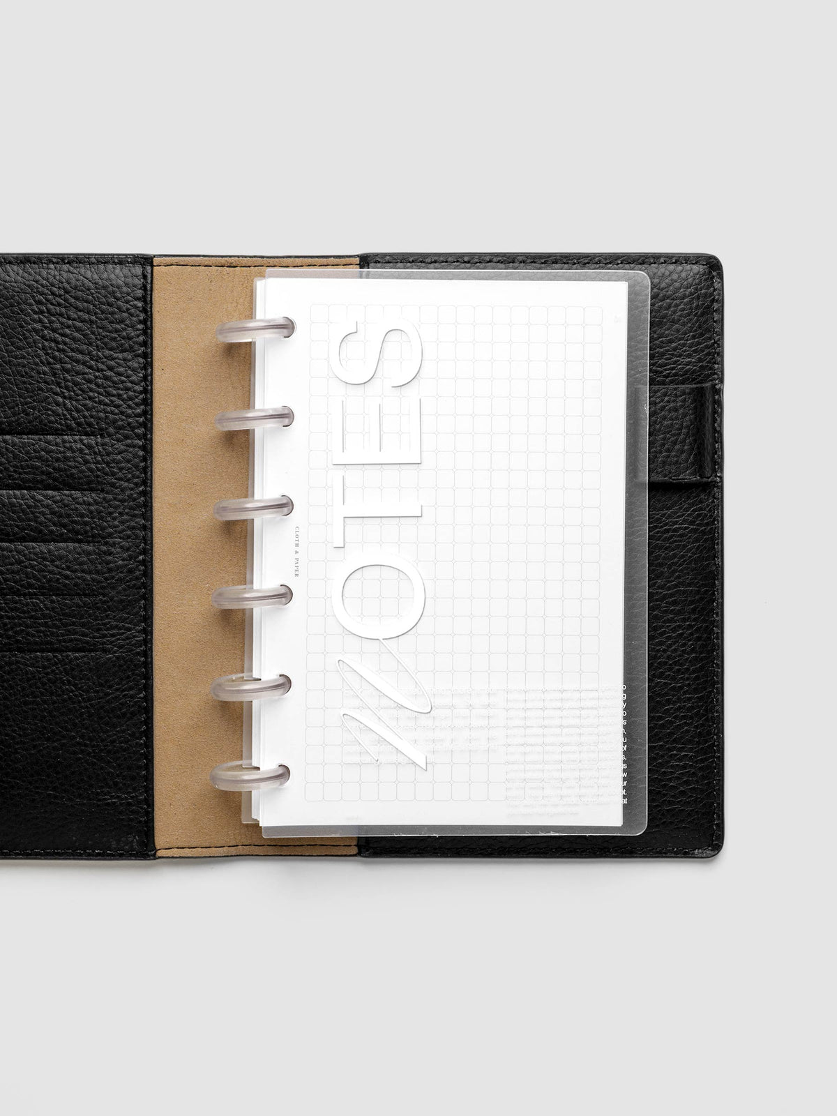 Clear plastic planner cover with white printed text shown pre-punched for CP Petite discbound planners in a black folio.