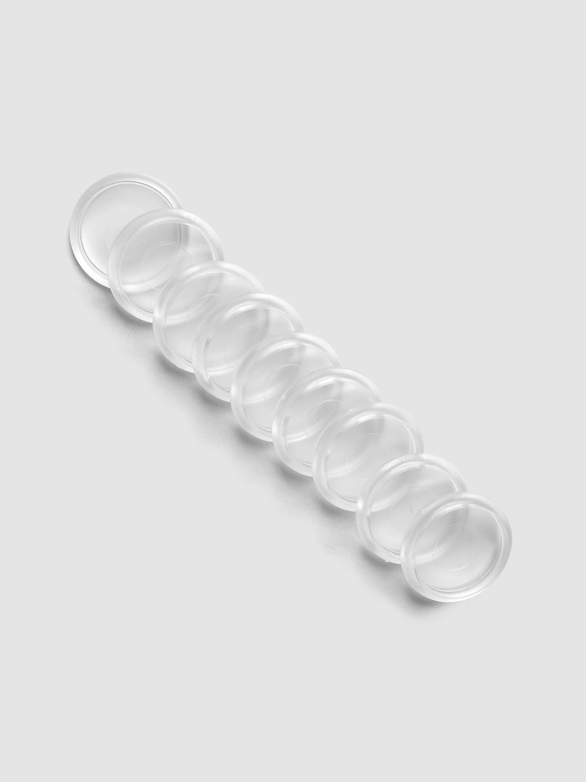 Set of 9 clear, transparent 1 inch planner discs laying diagonal on a grey background.