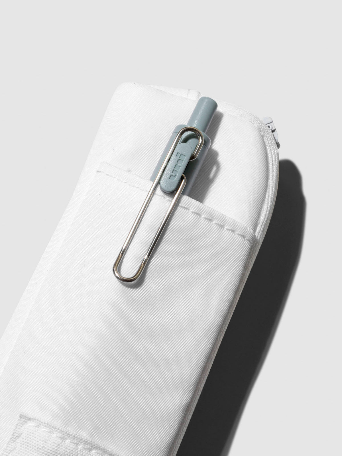 Uni Ball One pen displayed inside the external pocket of a notebook pouch. Color shown is Le Blanc.