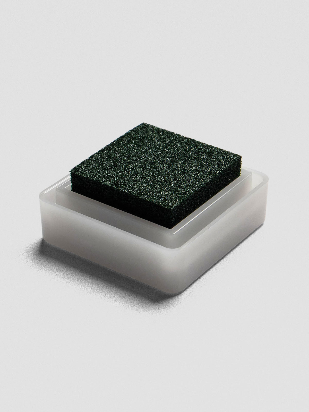 Side view of open Evergreen ink pad with green foam pad resting in white plastic base.