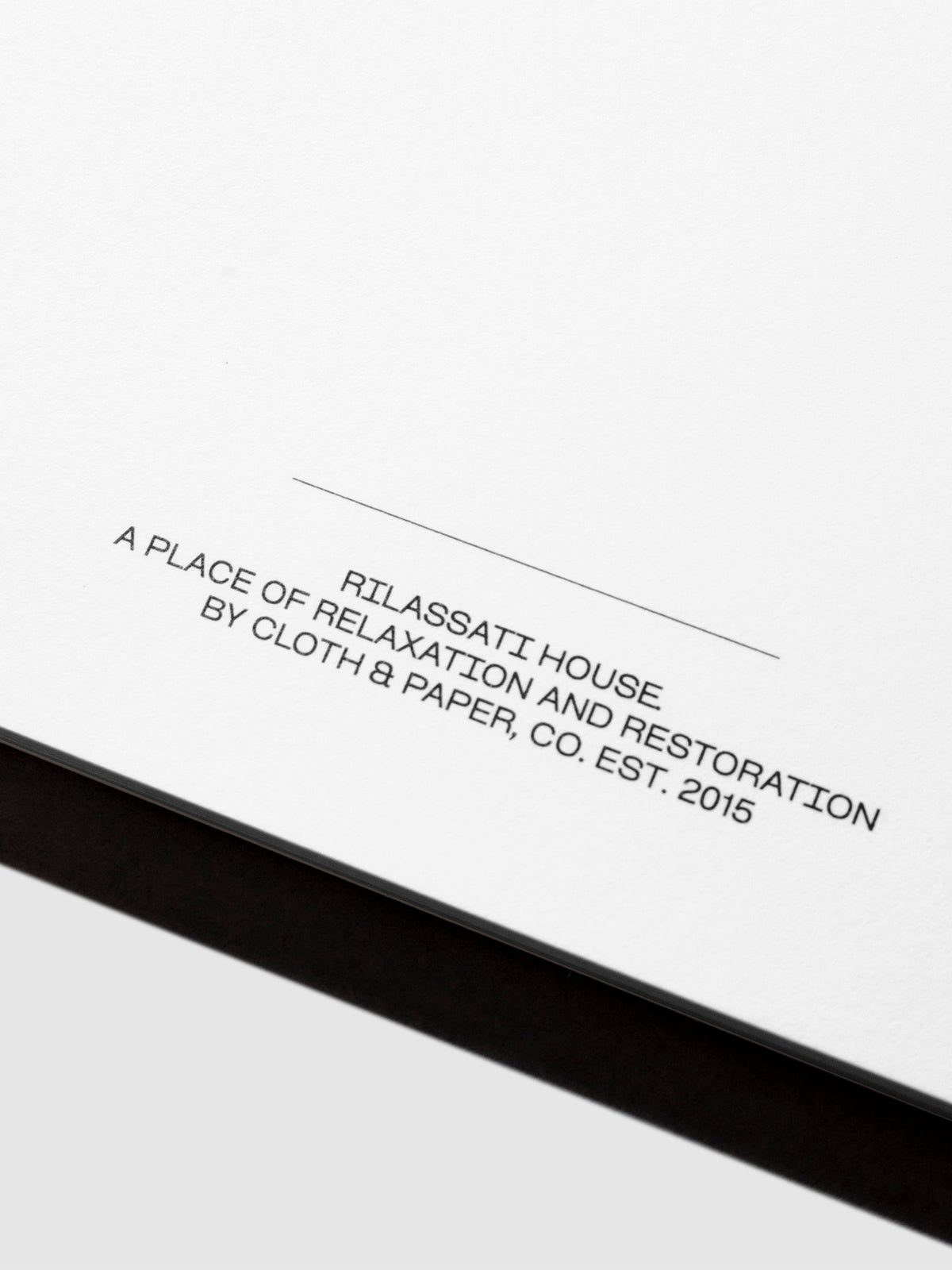 Closeup of notepad's footer text, which reads " RILASATTI HOUSE / A PLACE OF RELAXATION AND RESTORATION / BY CLOTH & PAPER, CO. EST. 2015"