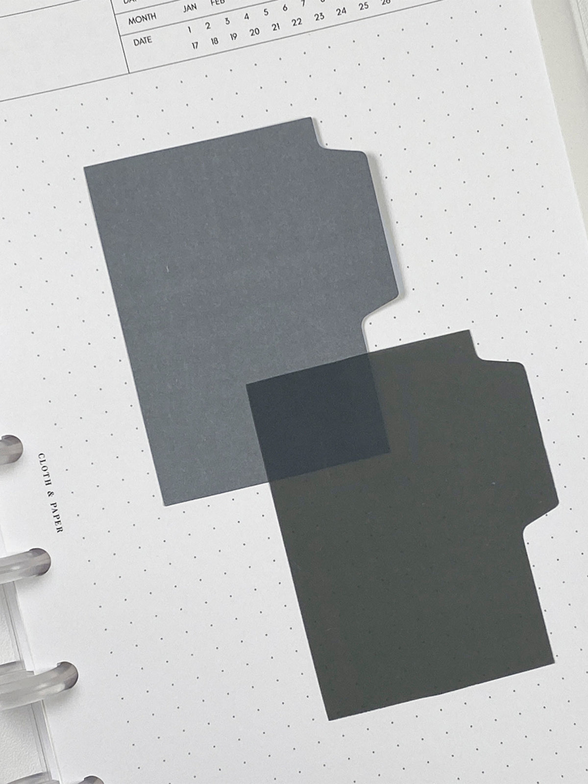 Blank Tab Sticky Note Set, Stone, Cloth and Paper. One matte and one transparent sticky note from the set placed on a task insert. The transparent sticky note is layered over the bottom right corner of the matte sticky note.