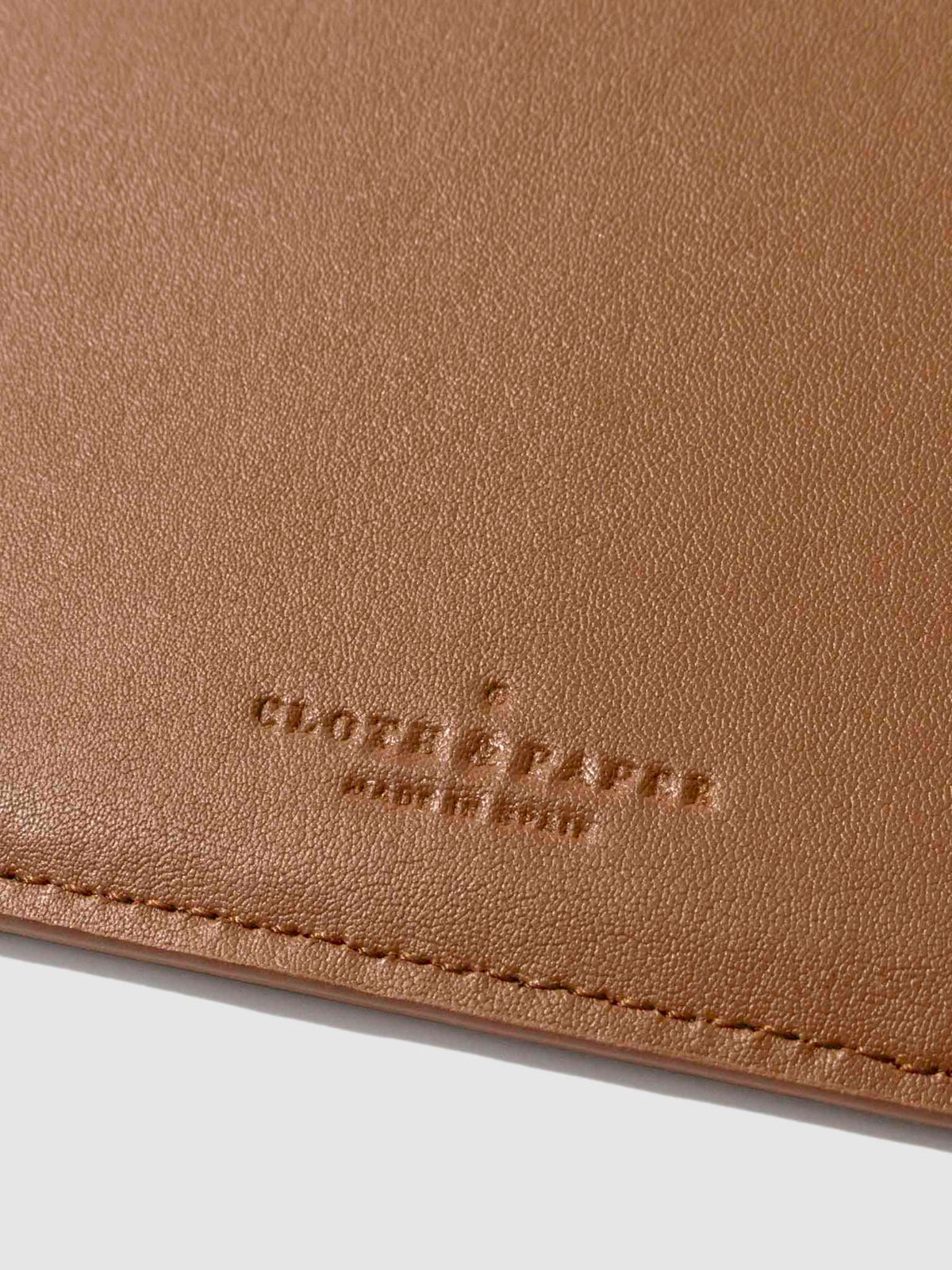 Closeup of clay brown folio's textured vegan leather and stamped Cloth and Paper logo.