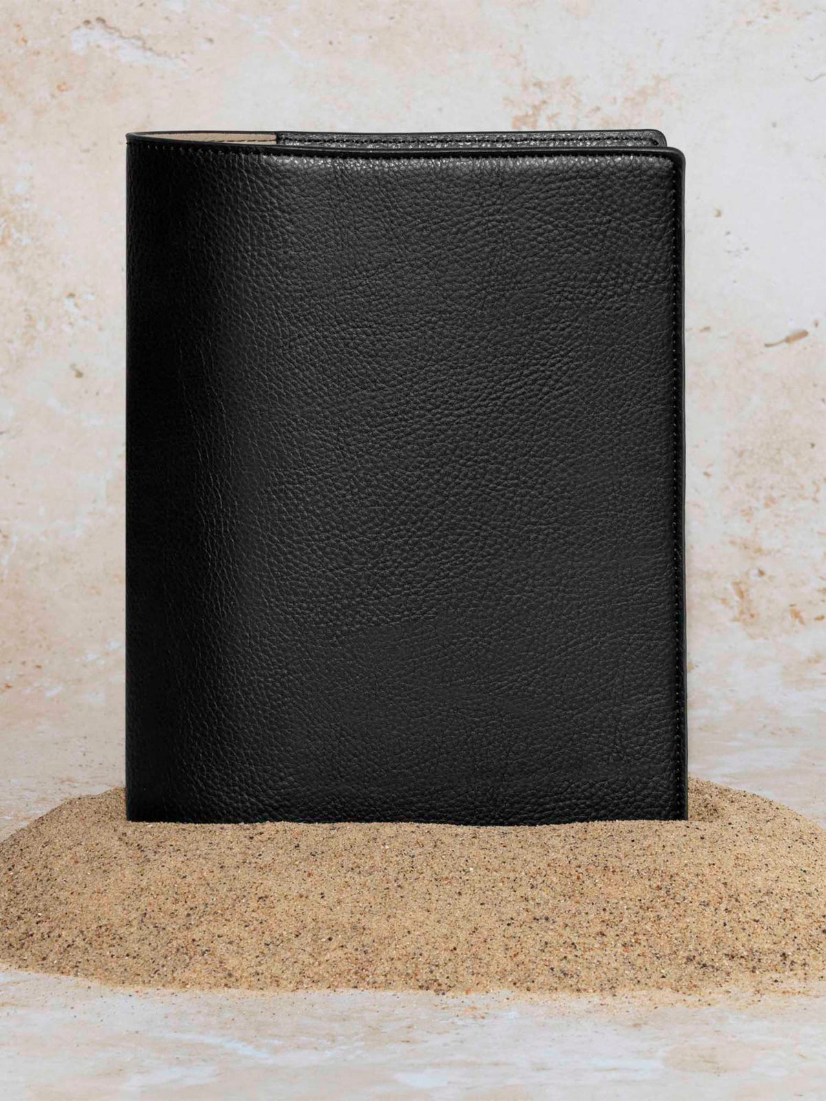 Cactus Vegan Leather Folio, Half Letter, Cloth and Paper. Folio displayed on a textured tan background, placed in a pile of sand. Color pictured is mesa black.