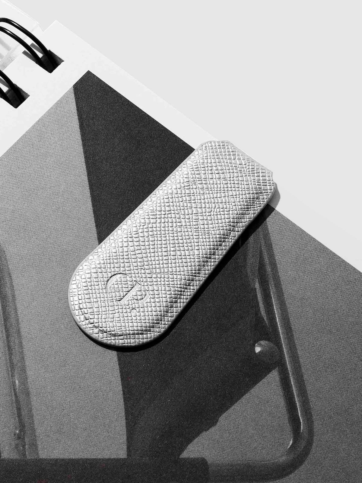 Silver clip shown attached to a notebook.