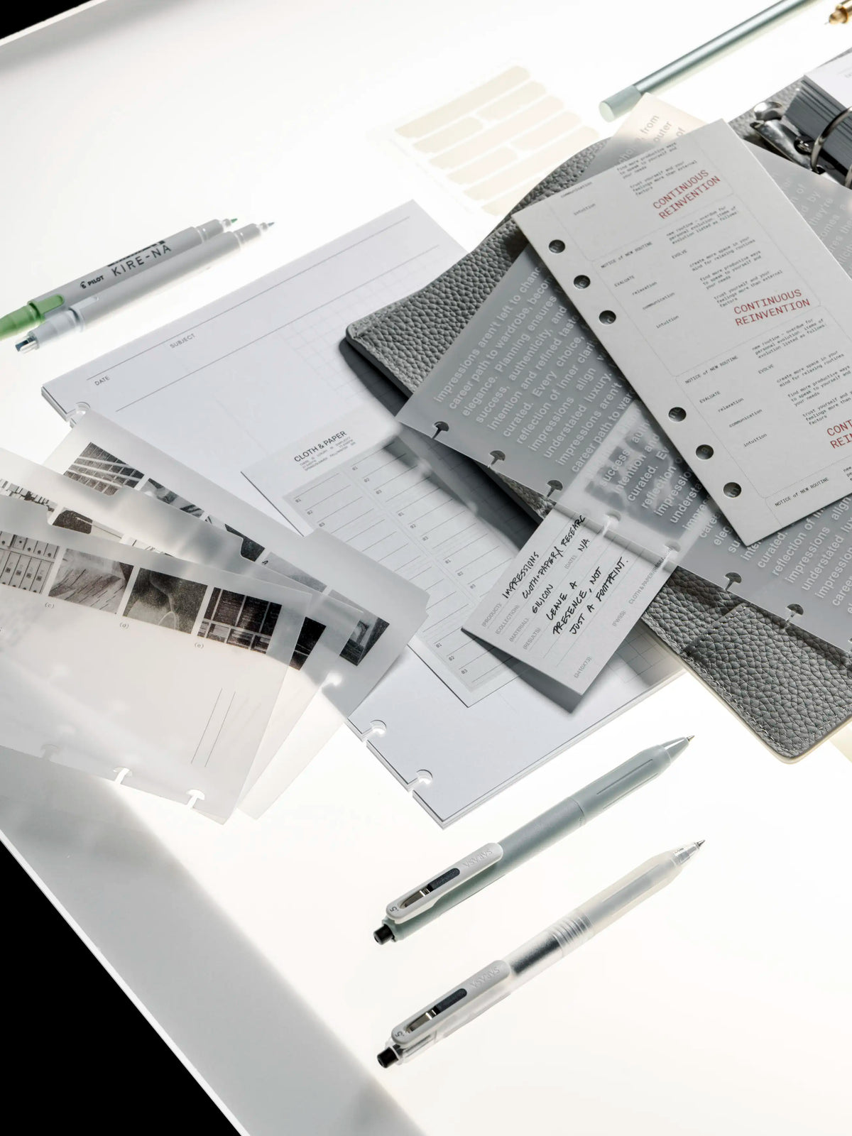 Collection of stationery items including pens, notebooks, and planner dashboards on a white surface.
