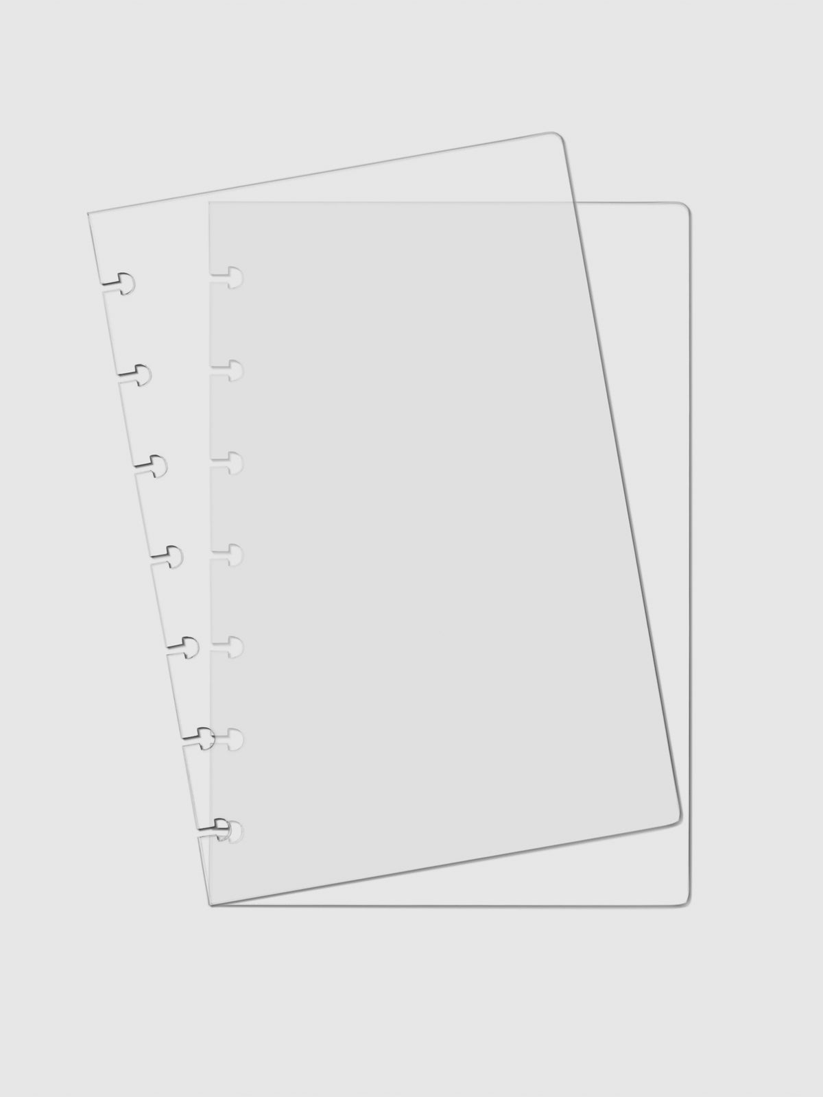 Two Crystal Clear Discbound Notebook Covers laid on top of one another with the top cover tilted slightly to the left.