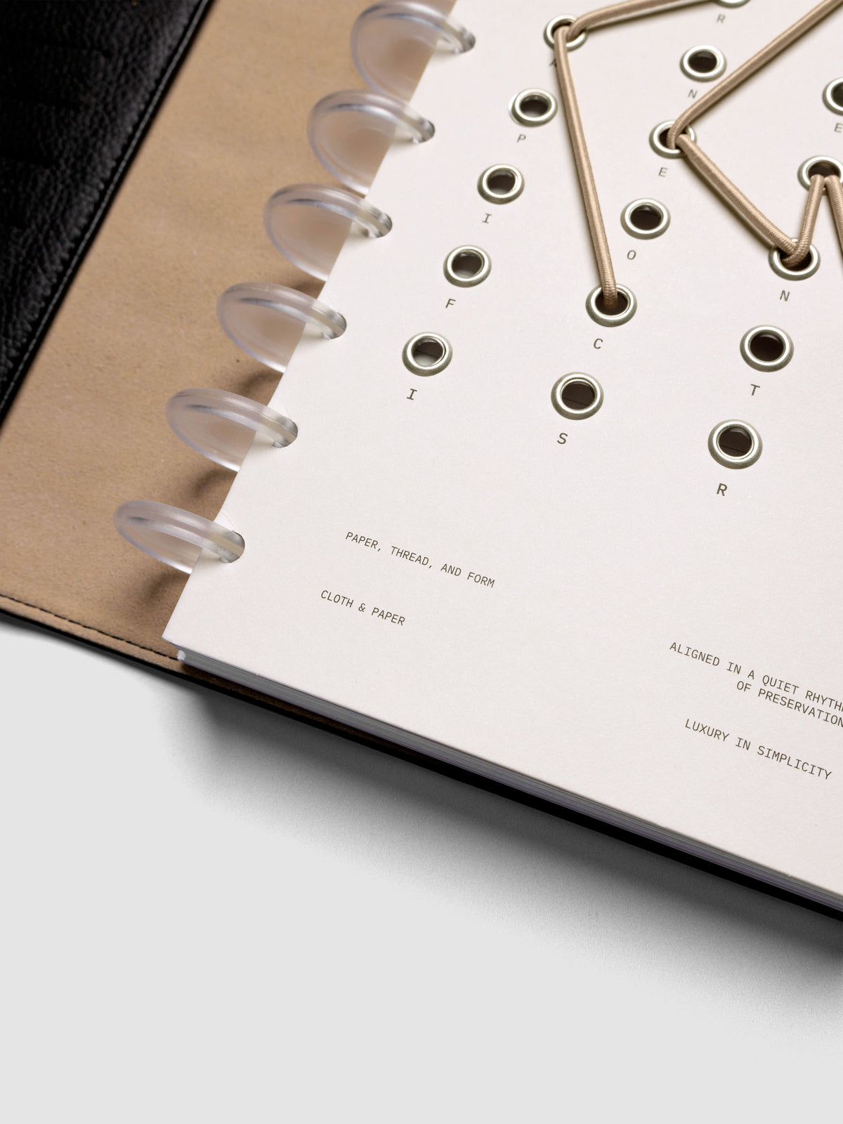 Cadence Dashboard with grommets and string on beige cardstock shown close up in a discbound planner.