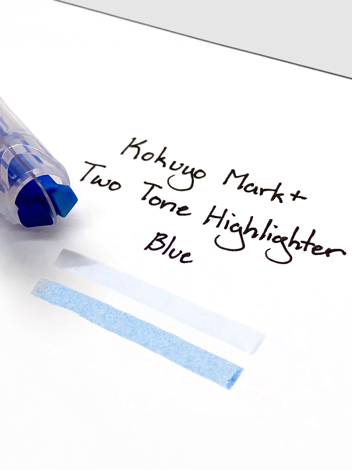 Close up on the dual tip nib of the highlighter. The highlighter is resting on a piece of paper displaying a writing sample.