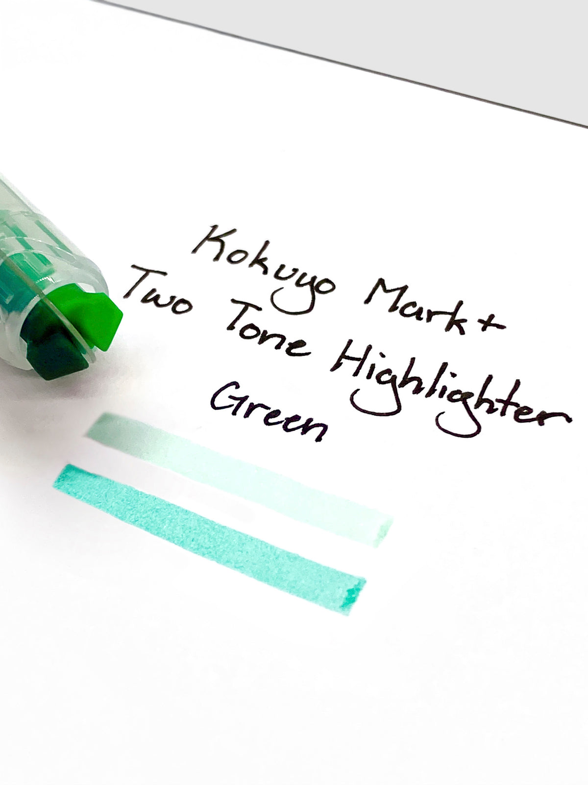 Close up on the dual tip nib of the highlighter. The highlighter is resting on a piece of paper displaying a writing sample.