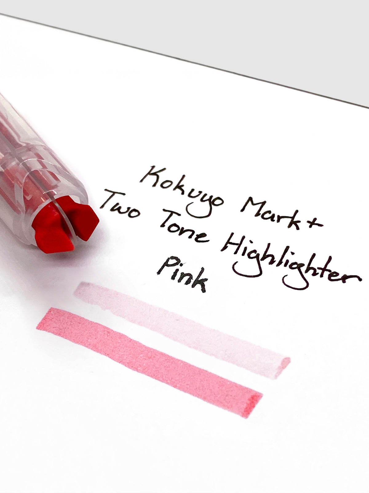 Close up on the dual tip nib of the highlighter. The highlighter is resting on a piece of paper displaying a writing sample.