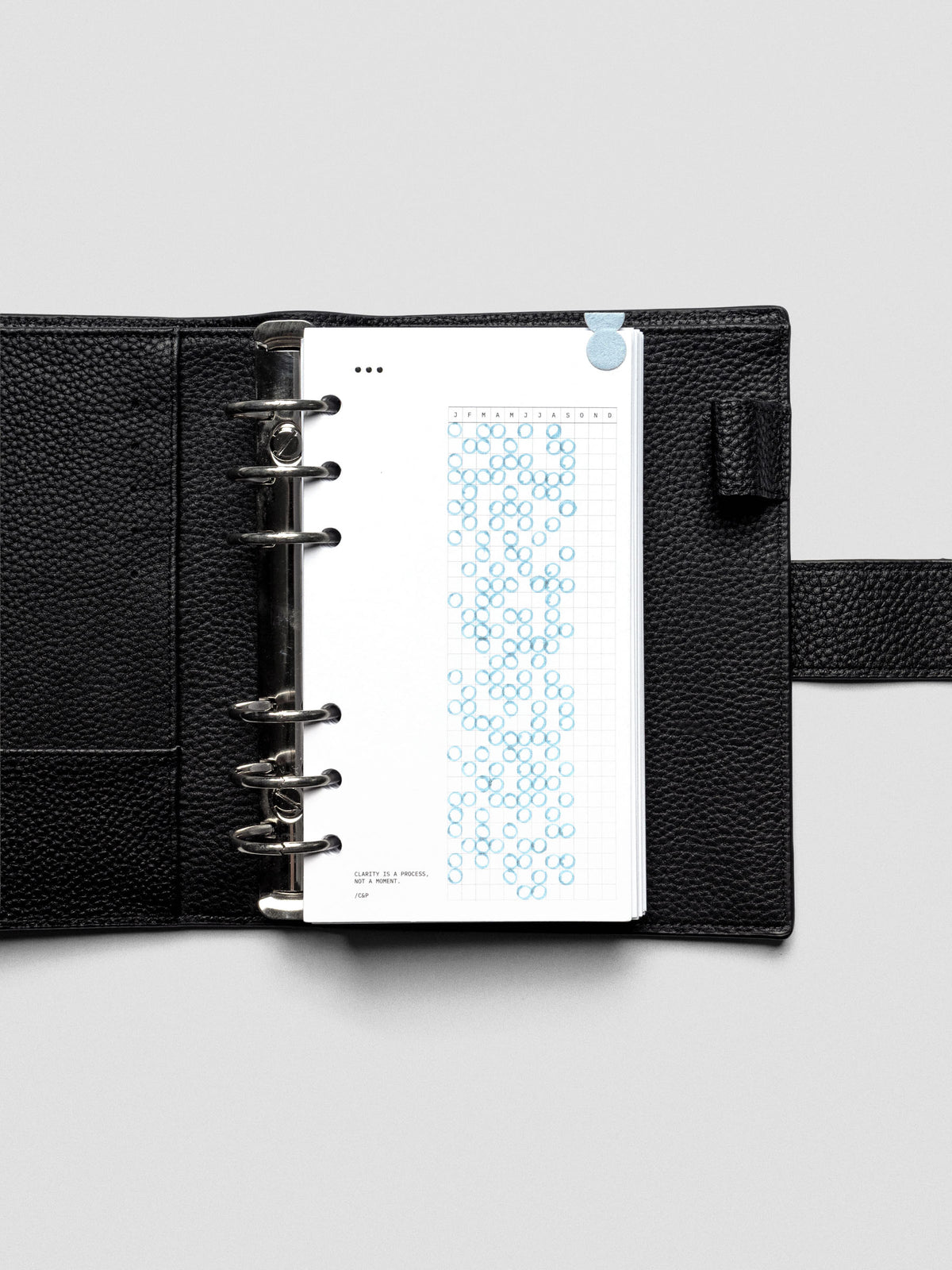 Mindful Moments Planner Dashboard in Personal size shown filled out with a blue highlighter in a ring bound leather planner cover.