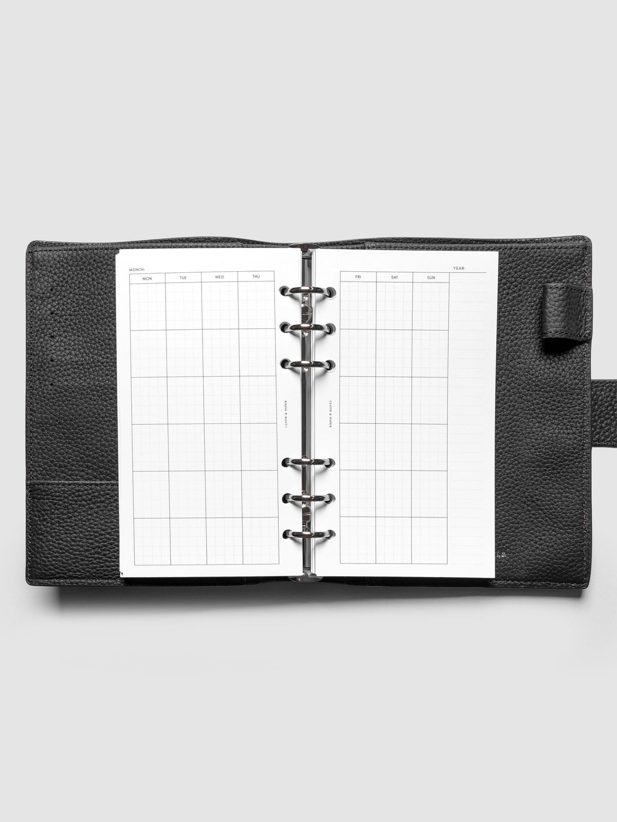 Personal Monthly Graph Planner Inserts shown ringbound in a black leather agenda.