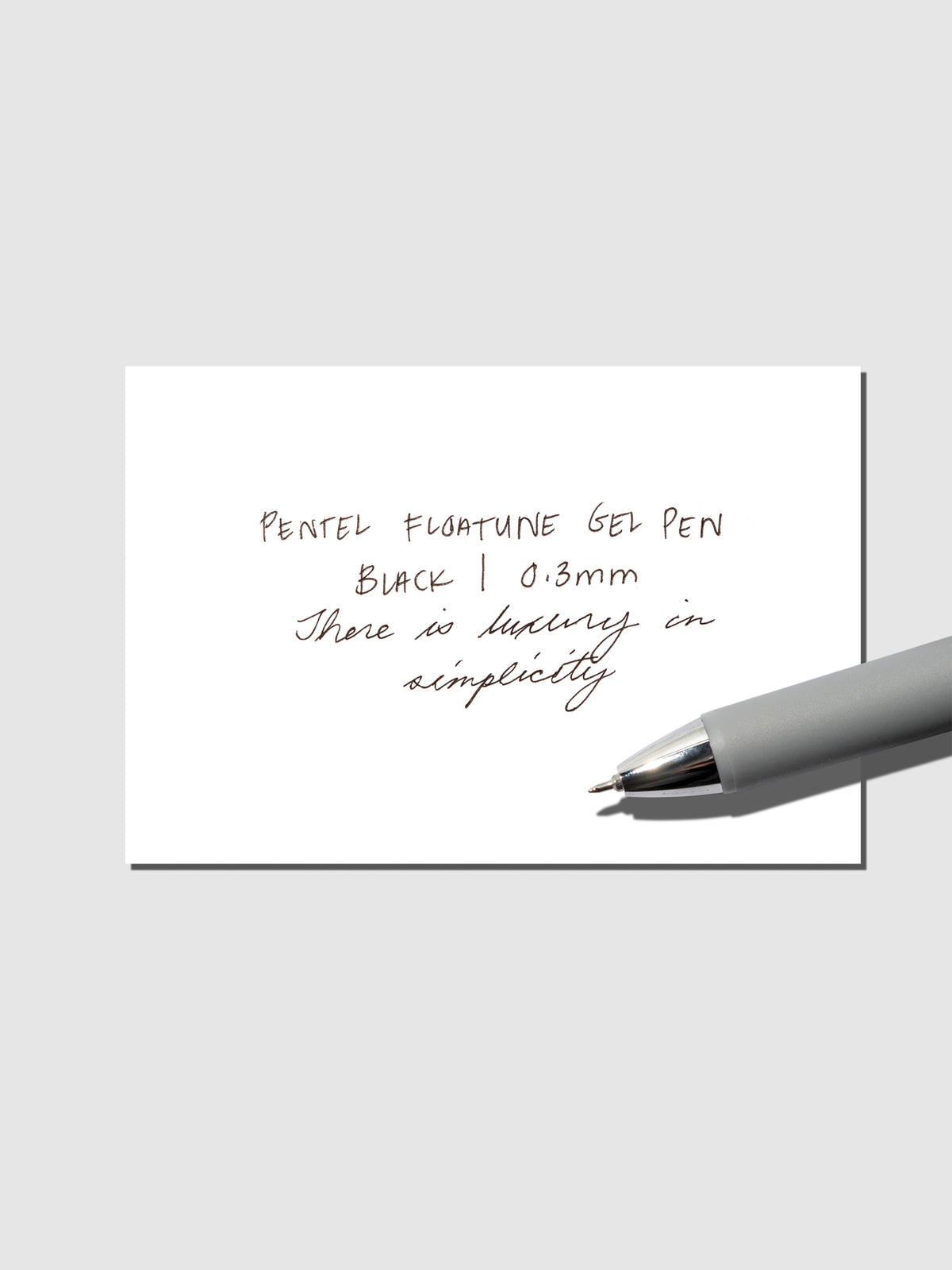 Pentel Floatune Gel Pen 0.3mm black ink. Pen resting on pen test sheet displaying writing sample.