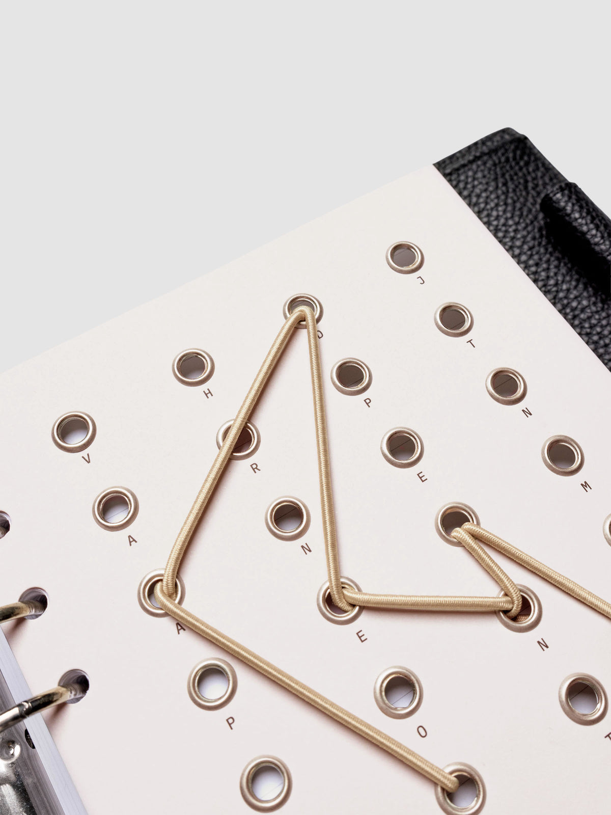 Cadence Dashboard with grommets and string on beige cardstock shown close up in a 6-ring planner.