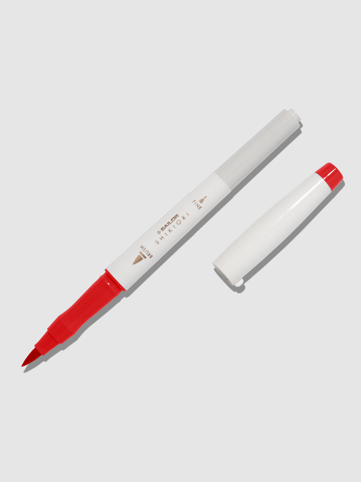 Brush pen displayed on a neutral background. It is uncapped with its brush nib exposed, and the cap lying parallel to the marker. Color pictured is Irori.