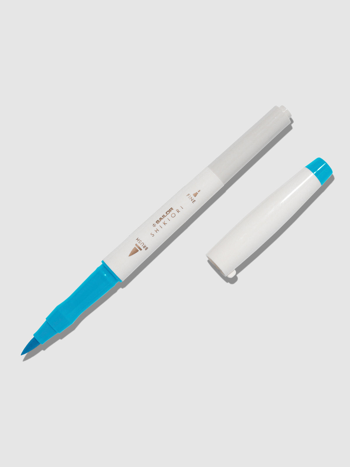 Brush pen displayed on a neutral background. It is uncapped with its brush nib exposed, and the cap lying parallel to the marker. Color pictured is Yukiakari.