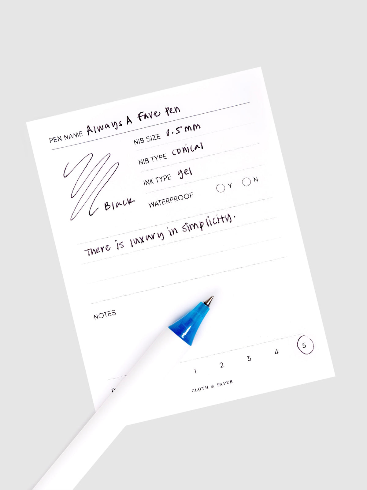Always a Fave Pen, Dark Blue, Cloth and Paper. Pen resting on pen test sheet displaying writing sample.