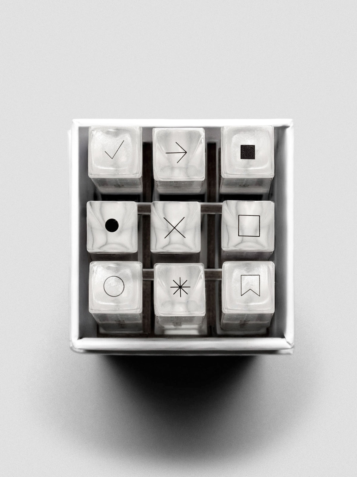 Overhead view of the nine stamp sticks arranged in a 3x3 grid inside the box, icons visible on top.