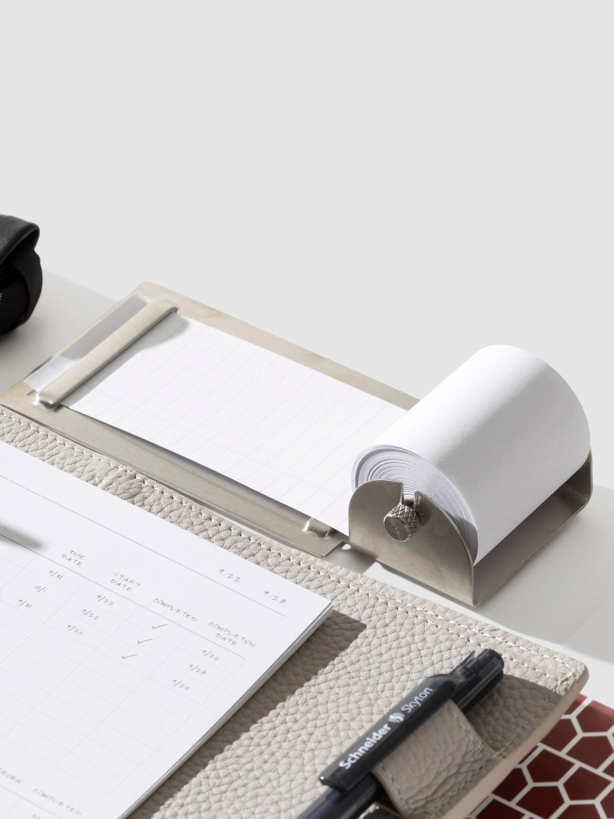 Task roller shown next to a leather agenda on a neutral background.