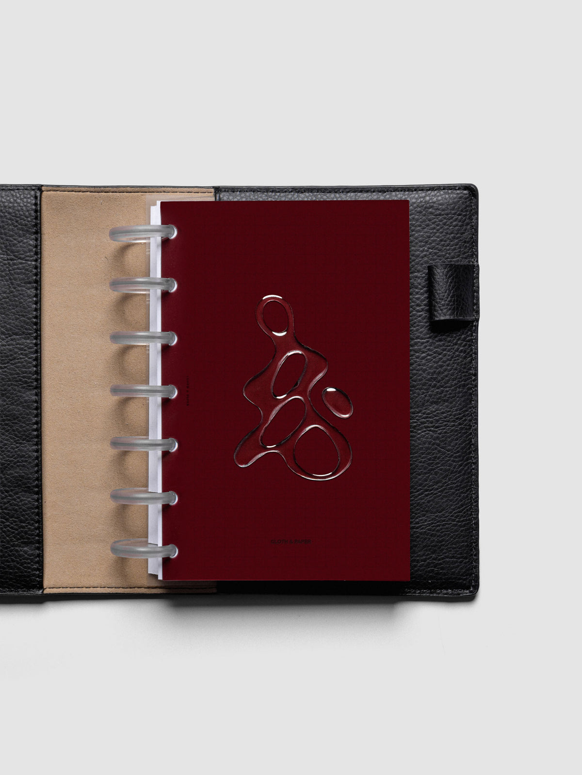 Dark red, semi-transparent, and glossy plastic planner dashboard with organic raised shape design in size HP Mini discbound in a black leather folio.