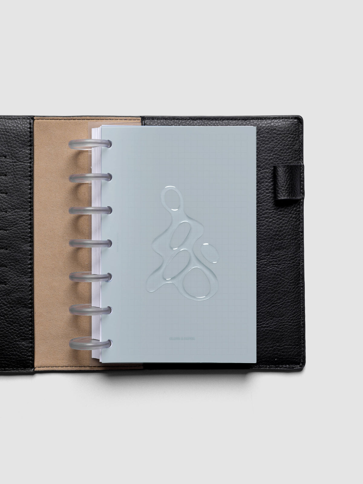 Light blue, semi-transparent, and glossy plastic planner dashboard with organic raised shape design in size HP mini discbound in a black leather folio.