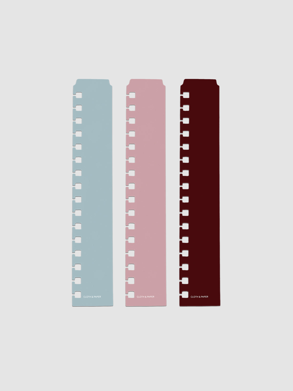 Set of three narrow page markers pre-punched for A5 Spiral planners in light blue, pink, and burgundy on a neutral background.