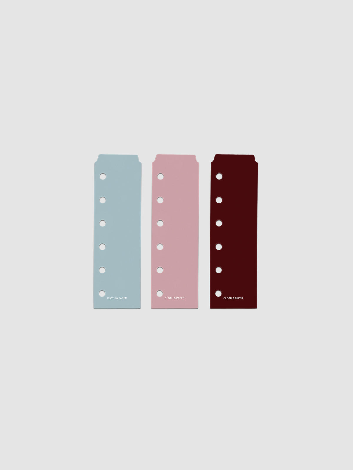 Set of three narrow page markers pre-punched for Pocket planners in light blue, pink, and burgundy on a neutral background.