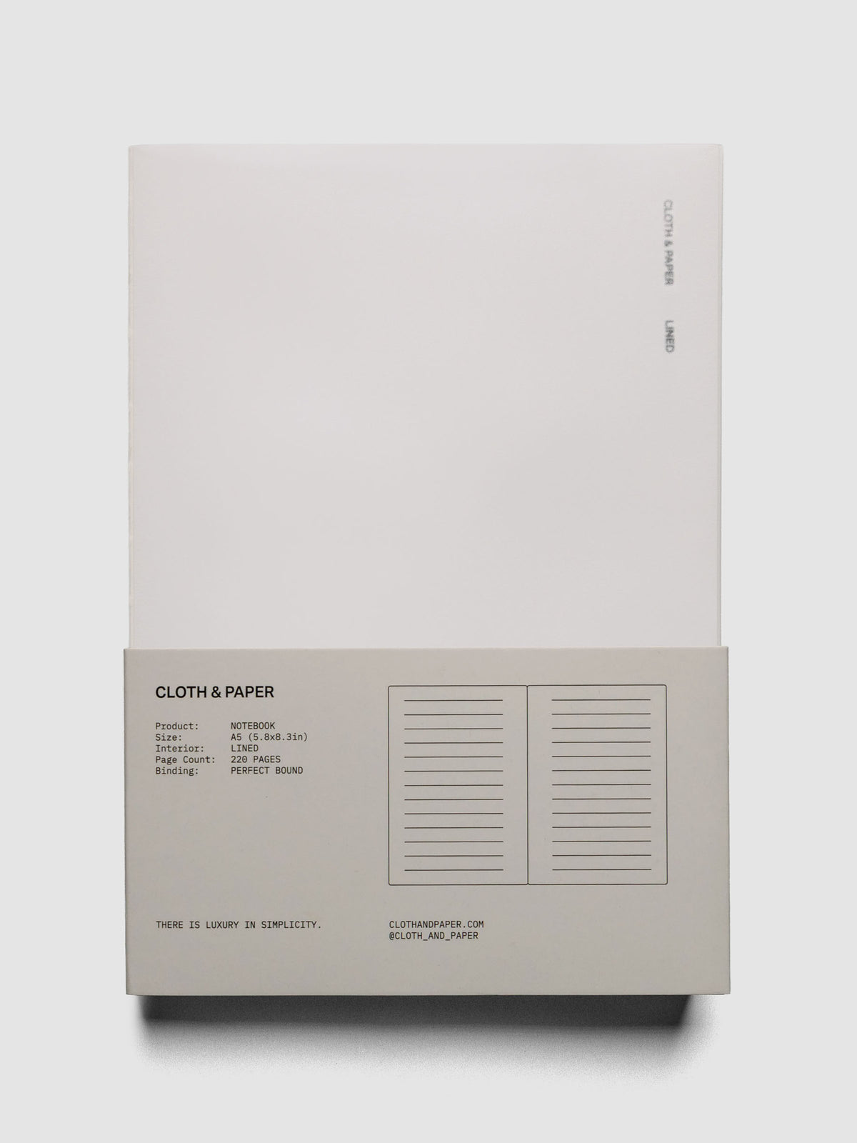 Perfect Bound Notebook | A5 | Lined | Ash shown open, laid flat, on a neutral background in packaging.