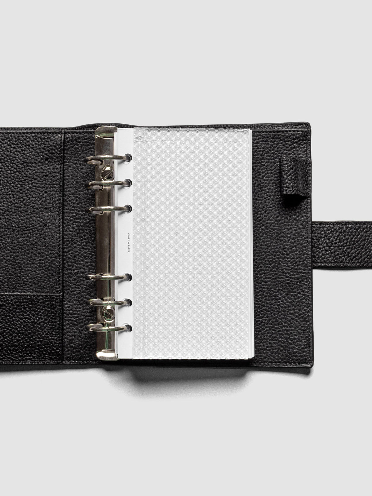 Clear, textured Studded Planner Dashboard in the size Personal, shown ringbound in a black leather agenda.