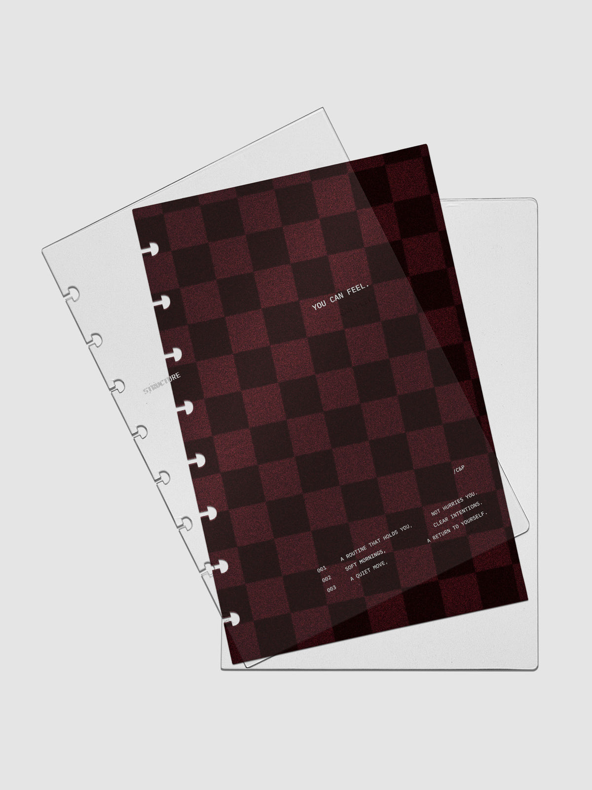 Half Letter sized velvet checkered dashboard in the color Bordeaux in between two crystal clear plastic planner covers with text printed on the cover on the theme of structure and routines.