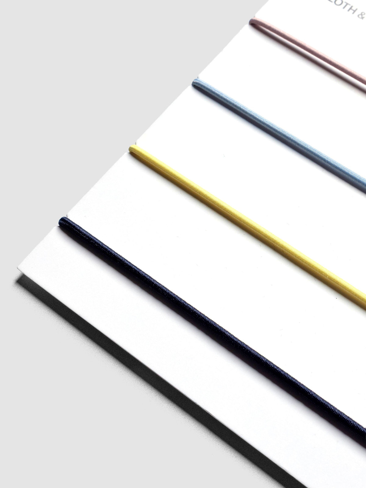 Close up image of a set of four exterior bands on a backing card in the colors light pink, light blue, yellow, and navy.