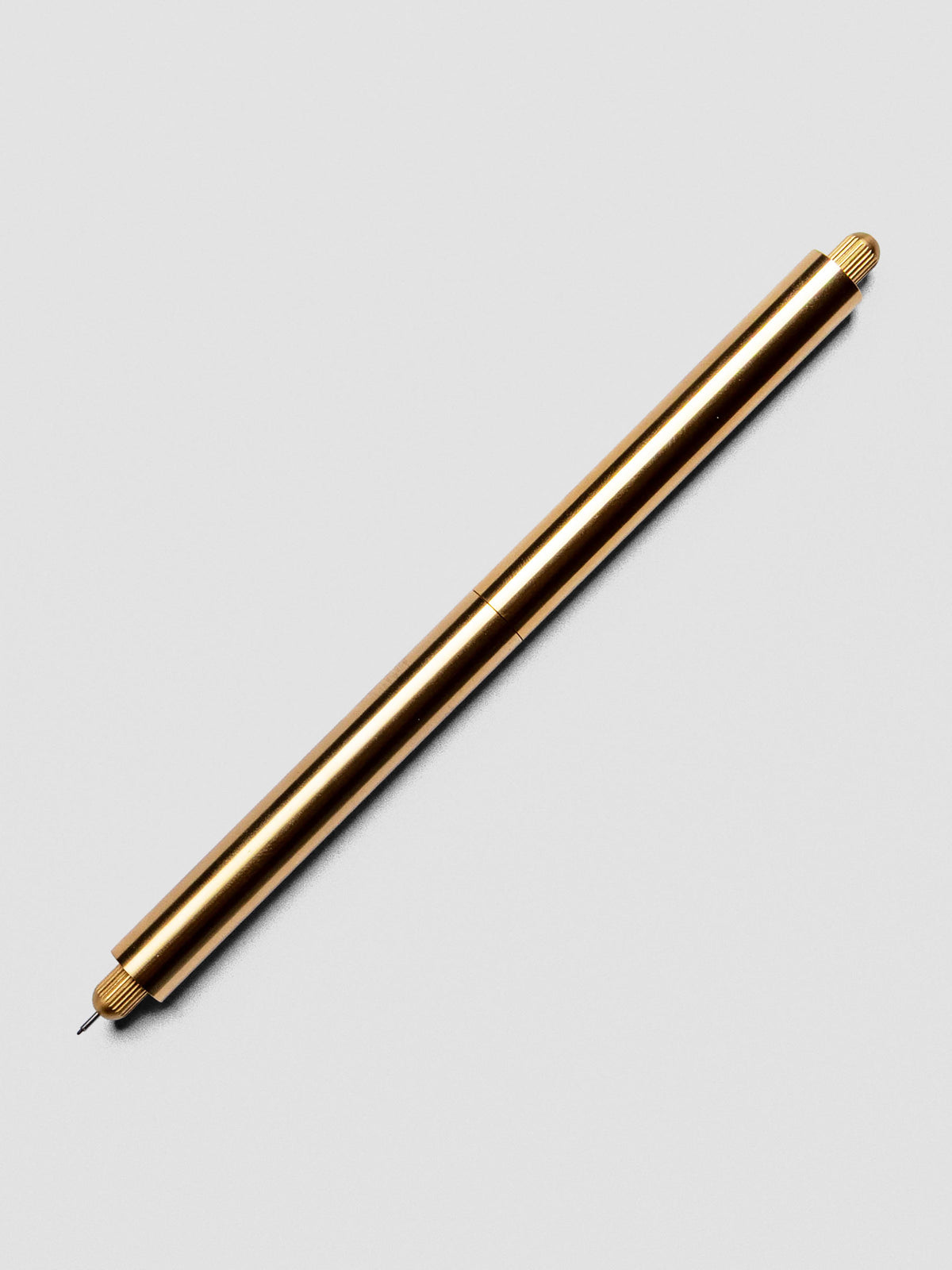 Brass Lumos Pro Duo Tip Pen placed beside its cap on an neutral background.