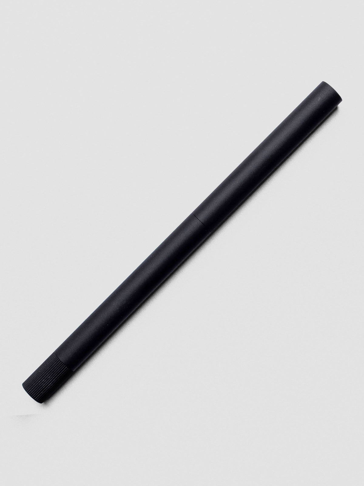 Matte Black Lumos Pro Duo Tip Pen resting diagonally on an open notebook, capped.