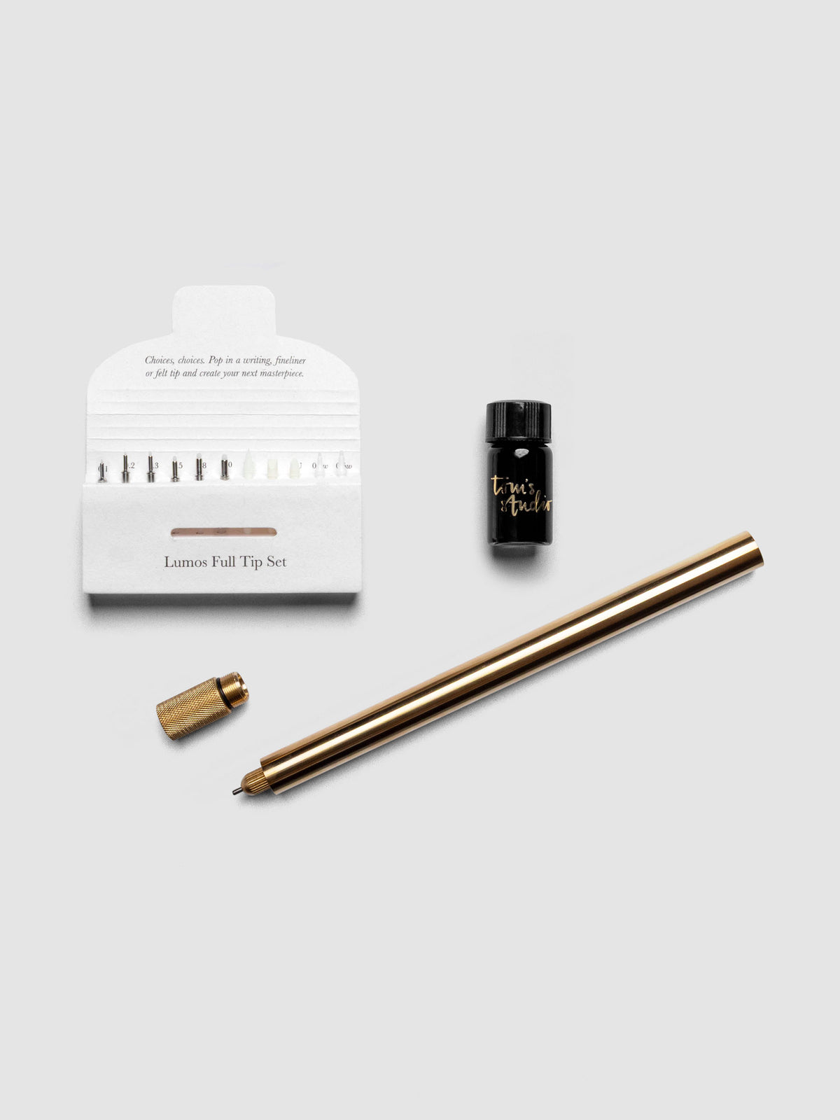 Brass Lumos Pro Single Tip Pen diagonally, uncapped, with nib set and ink resevoir.