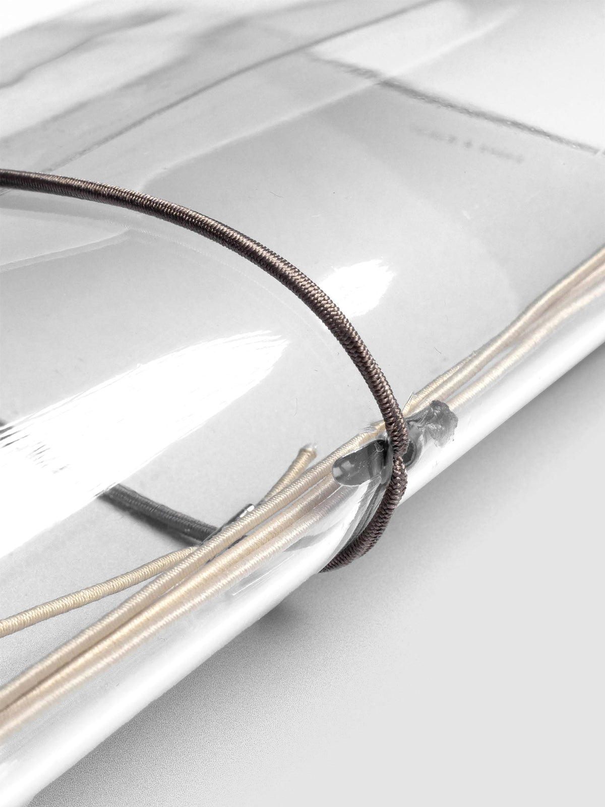 Dark brown elastic exterior band looped through clear vinyl cover spine.