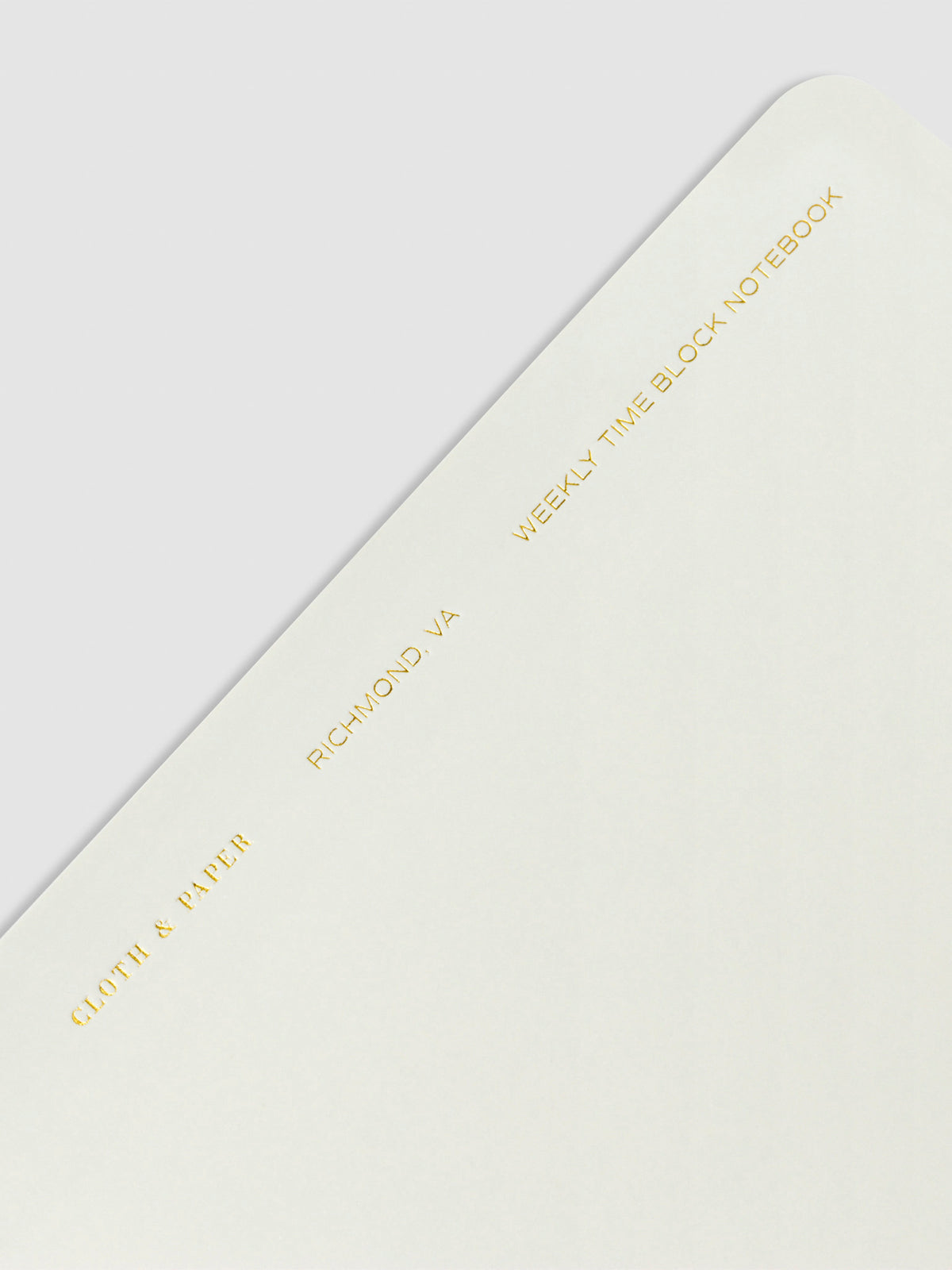 Closeup of text at the top of the notebook. Text reads "Cloth and Paper, Richmond, VA, Weekly Time Block Notebook" in gold foil print.